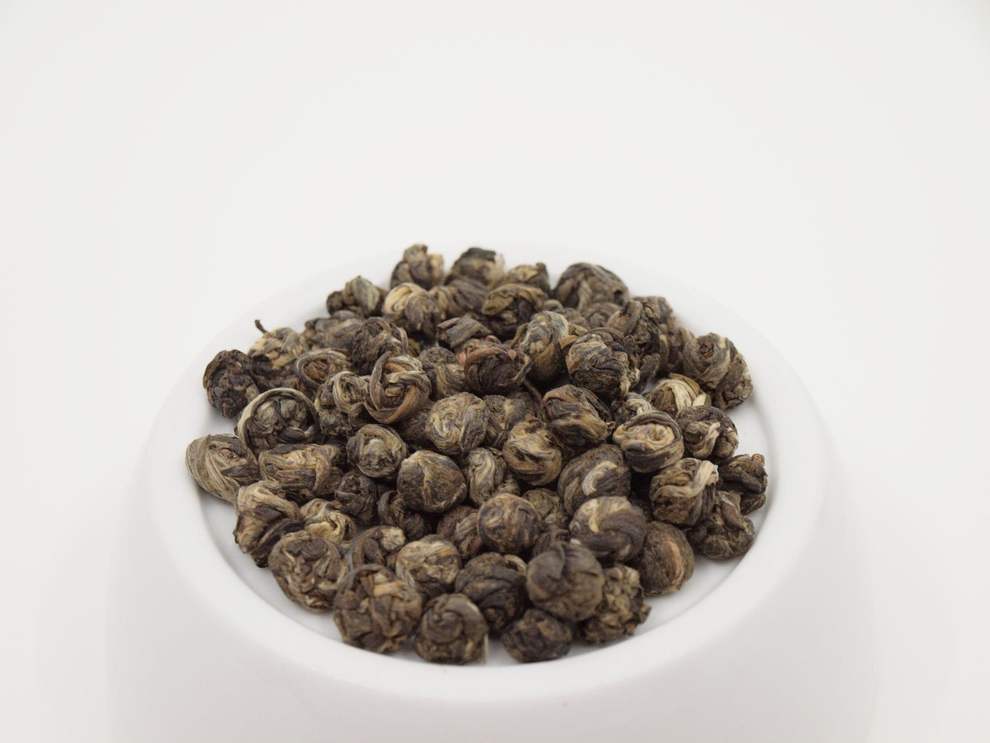 jasmine pearl green tea resting on an elevated white porcelain dish