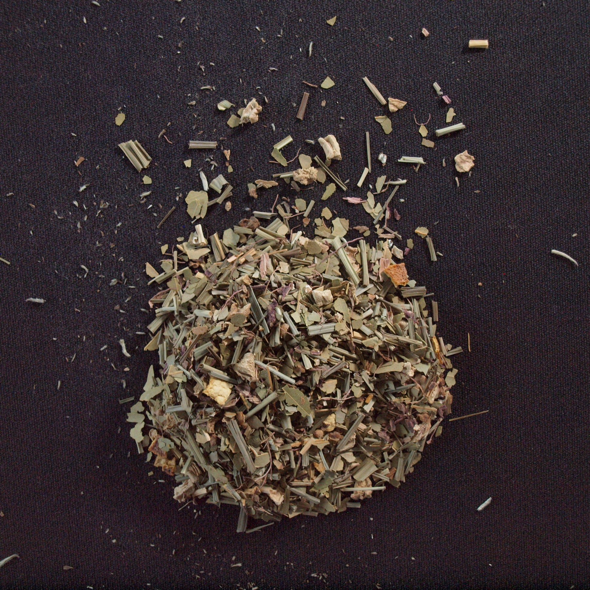 Loose Celestial Chai (Decaf) herbal chai tea scattered on a dark surface