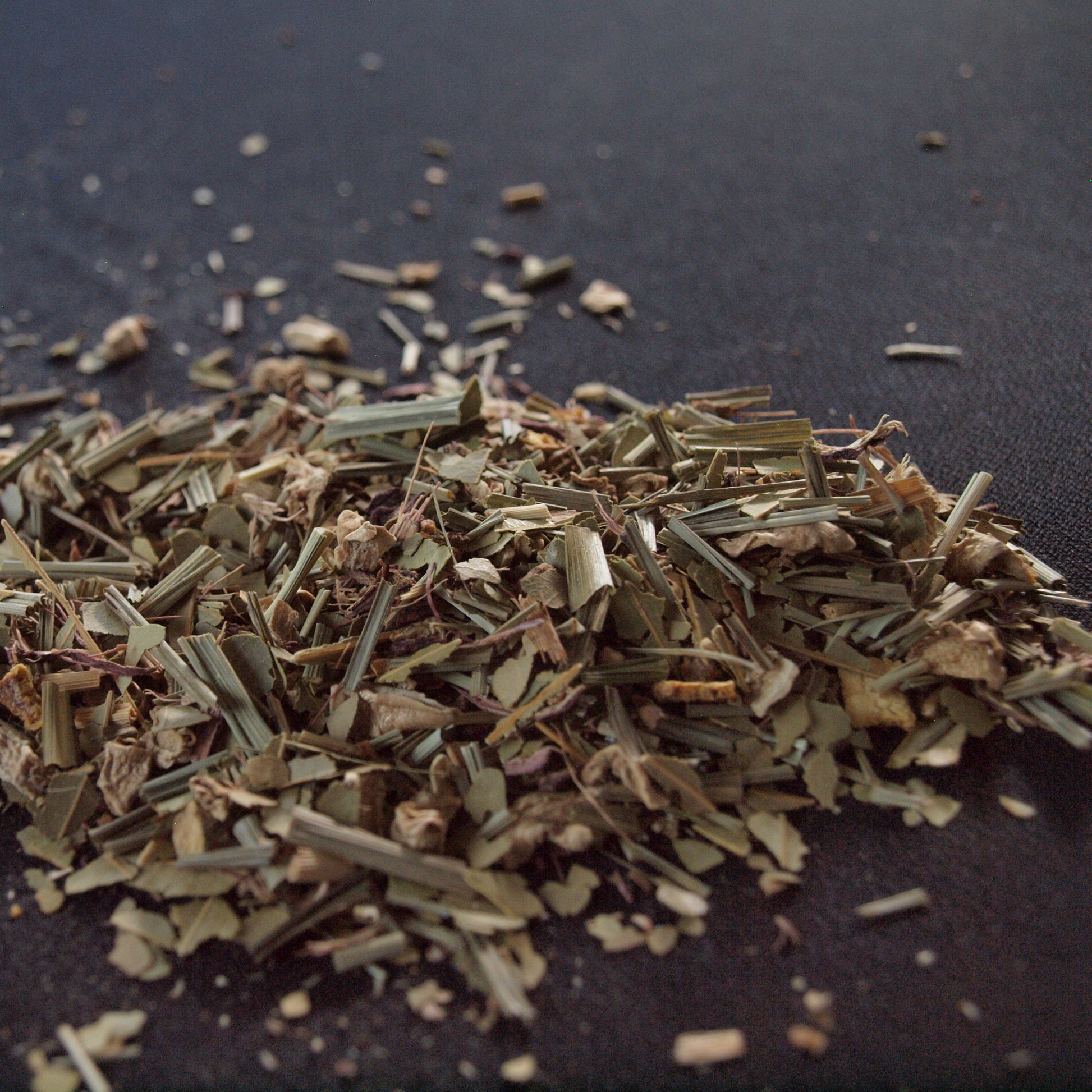 An arrangement of Celestial Chai (Decaf) tea ingredients spread out on a black background